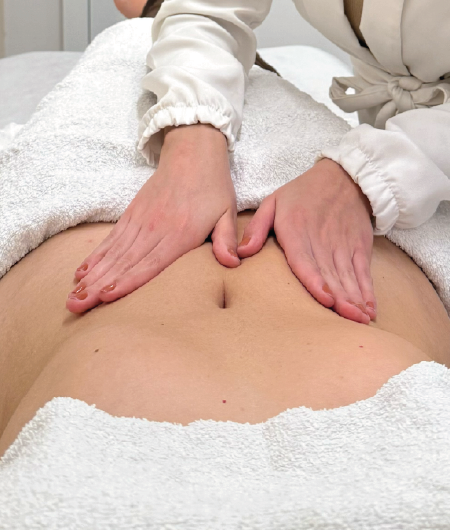 Profissional de estética realizando massagem de drenagem linfática manual na região do abdômen de uma cliente em uma clínica em Curitiba.